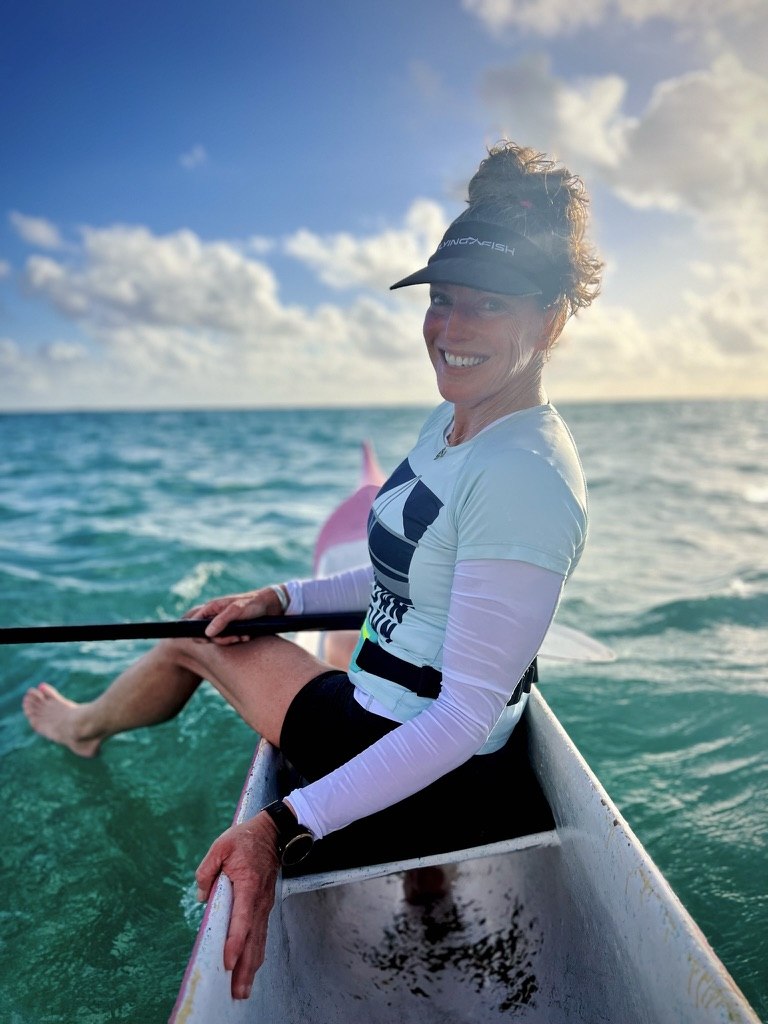 Kim seated in an outrigger canoe on turquoise water