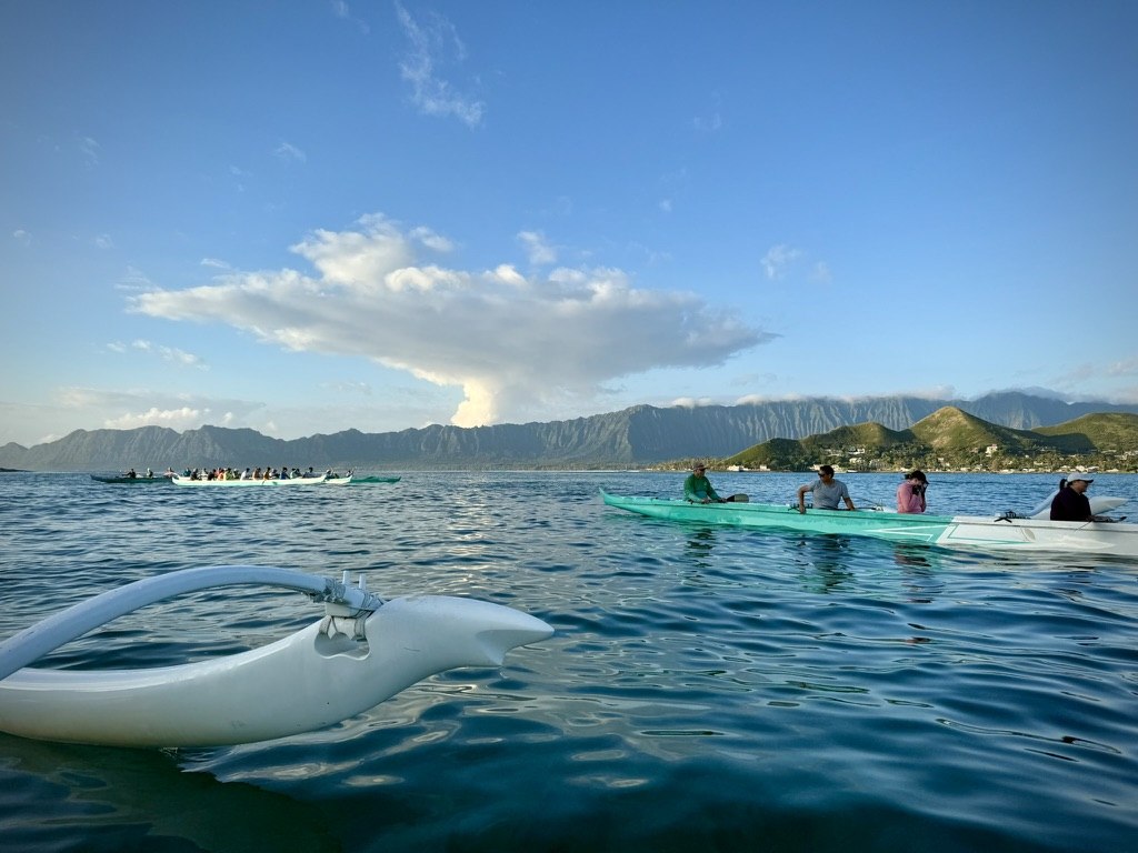 Outrigger canoes on the water with the Koolau mountains behind them